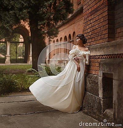 A young lady stands at the wall of an ancient castle looking with hope in the distance. Emotion waiting for the long Stock Photo