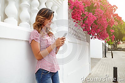 Young lady texting outdoors on pink flowers street Stock Photo