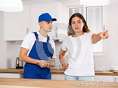 Young landlady explains her problem to a guy plumber Stock Photo