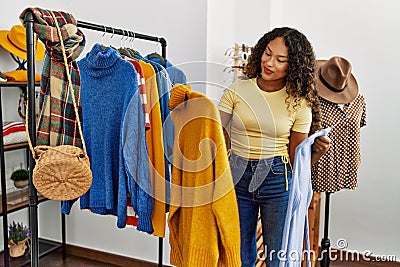 Young latin customer woman smiling happy choosing clothes at clothing store Stock Photo