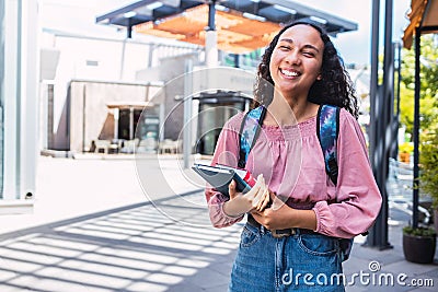 Confidence. Smiling latin university student woman standing and holding her books outside of the mall. Stock Photo