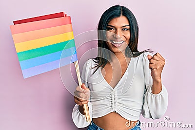 Young latin transsexual transgender woman holding rainbow lgbt flag screaming proud, celebrating victory and success very excited Stock Photo