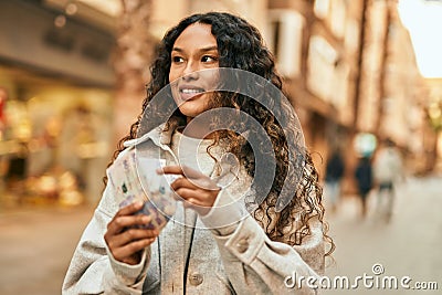 Young latin woman smiling happy counting colombia pesos banknotes at the city Stock Photo