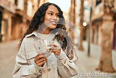 Young latin woman smiling happy counting colombia pesos banknotes at the city Stock Photo