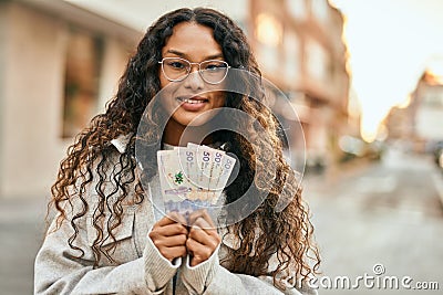 Young latin woman smiling happy holding colombia pesos banknotes at the city Stock Photo