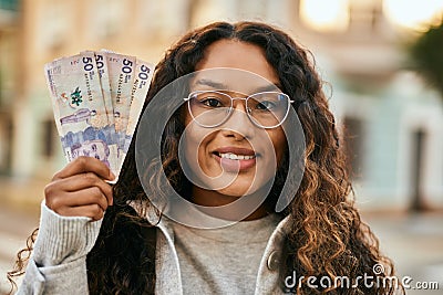 Young latin woman smiling happy holding colombia pesos banknotes at the city Stock Photo