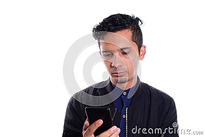 Young Latino man, serious and looking at his cell phone isolated on white background. Handsome man reading on his smart Stock Photo