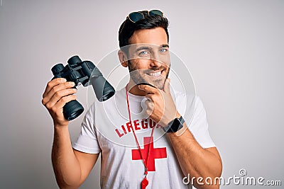 Young lifeguard man with beard wearing t-shirt with red cross and sunglasses using whistle looking confident at the camera smiling Editorial Stock Photo
