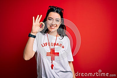 Young lifeguard woman wearing secury guard equipent over red background smiling positive doing ok sign with hand and fingers Stock Photo