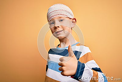 Young little caucasian kid injured wearing medical bandage on head over yellow background doing happy thumbs up gesture with hand Stock Photo