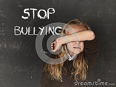 Young little cute schoolgirl scared sad covering her face and the words stop bullying text Stock Photo