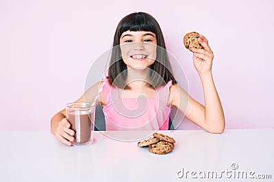 Young little girl with bang sitting on the table having breakfast smiling with a happy and cool smile on face Stock Photo