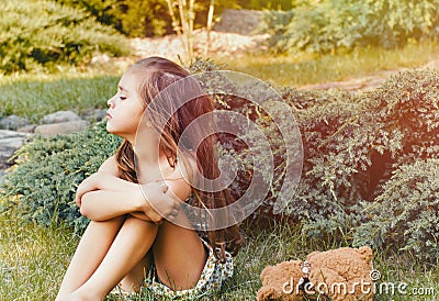 Young little naughty girl with toy outdoor in the park Stock Photo