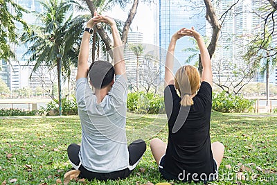 Young love couple making a meditation to calm their mind after exercising in park encircle with a warm light sunshine in afternoon Stock Photo