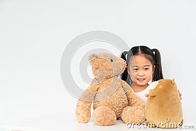 Young lovely Asian girl playing with 2 cute teddybear dolls at home, copy space on white wall background Stock Photo