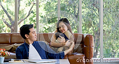 Young lovers spend time together on holidays in the living room. The young man wears comfortable clothes, hand a teddy bear to Stock Photo