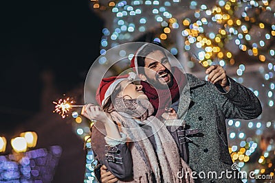 Loving couple burning sparklers by holiday illumination on new years eve Stock Photo