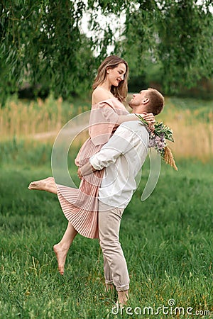 Young loving couple hugging and dancing on the green grass on the lawn. Beautiful and happy woman and man gently touch each other Stock Photo