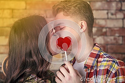Young, loving couple, kiss each other, cover their lips with a candy in the form of a heart, Teenagers, gentle kiss Stock Photo