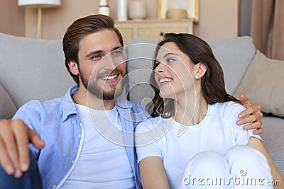 Young loving couple relaxing on floor near sofa together. Woman man embrace enjoy company of each other sitting on couch Stock Photo