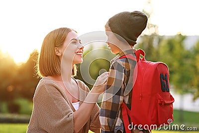 Young loving smiling mother leading little son schoolboy with backpack to first grade in school Stock Photo