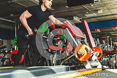 young male athlete performs exercises in the gym with dumbbells. Endurance Strength Training Stock Photo