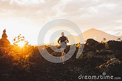 Young athlete trailrunning in mountains at sunrise Stock Photo