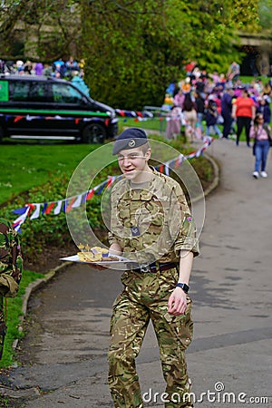 A Young Male Cadet in Uniform Carrying a Tray of Delicious Cakes at King Charles III's Coronation Event in Harrogate, UK. Editorial Stock Photo