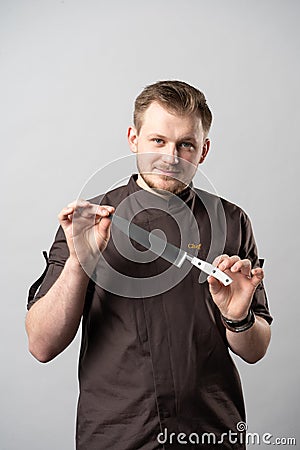 Chef in a uniform jacket, demonstrates a professional chef`s knife Stock Photo