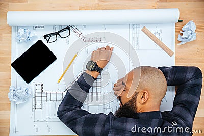 Young male designer lying and sleeping on table with blueprint Stock Photo