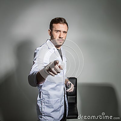 Young male dentist in a white coat holds a magnifying glass in front of his teeth and smiles. Concept humor in healthcare Stock Photo