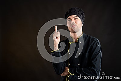 Young male dressed in a black chef suit with his finger up has come up with an idea Stock Photo