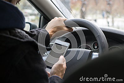 Young male driver uses mobile phone while driving car Stock Photo