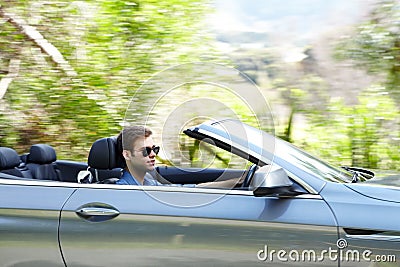 He loves his convertible. A young male driving a silver convertable. Stock Photo