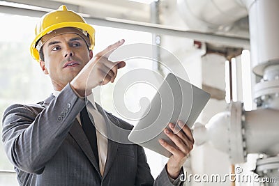 Young male engineer with digital tablet pointing away in industry Stock Photo