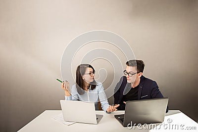 Young male and female business partners sitting behind a computer monitor and thinking of something Stock Photo