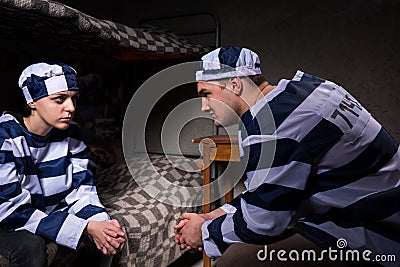 Young male and female prisoners wearing prison uniform sitting a Stock Photo