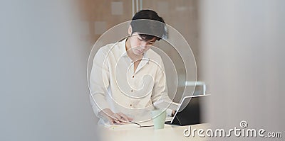 Young male freelancer reading notebook while working on his concepts for the next project Stock Photo