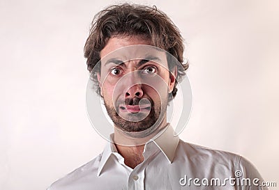 Young male with a frightened face against a white wall Stock Photo
