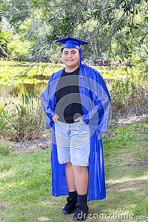 Young Graduate Posing With Cap And Gown In A Nature Setting Stock Photo