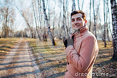 Young male walking in the forest in nature in a cream coat Stock Photo