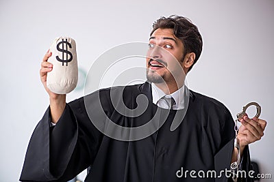 Young male judge holding moneybag in corruption concept Stock Photo