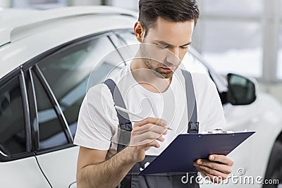 Young male maintenance engineer holding clipboard in repair shop Stock Photo