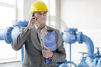 Young male manager with clipboard using cell phone in industry Stock Photo