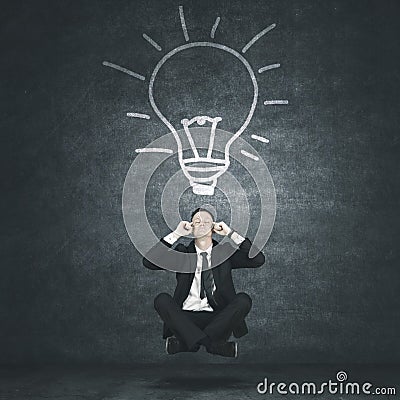 Male manager levitating under light bulb Stock Photo