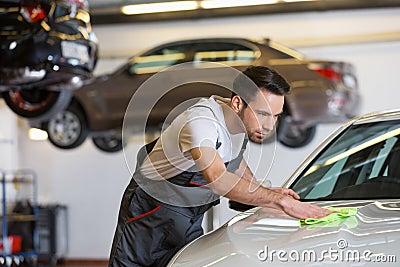 Young male mechanic cleaning car in repair shop Stock Photo