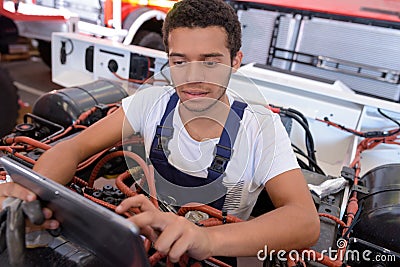 Young male mechanic using tablet while working on industrial vehicle Stock Photo