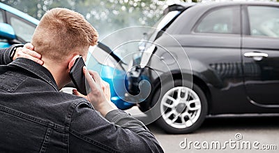 Young Male Motorist Involved In Car Accident Calling Insurance Company Or Recovery Service Stock Photo