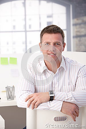 Young male office worker sitting in office smiling Stock Photo