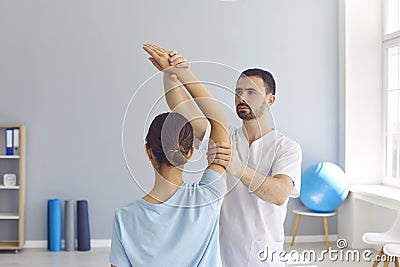 Young male osteopath masseur in white clothes kneads the joints of the girl`s hand. Stock Photo